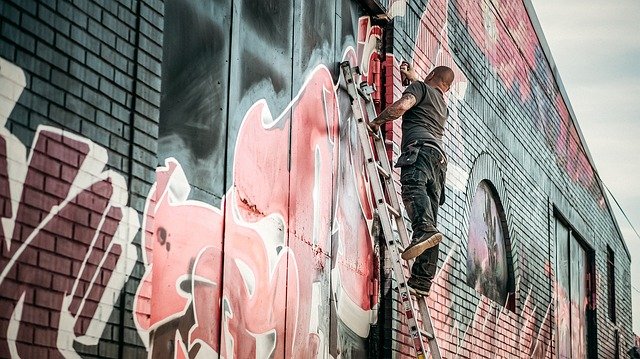 muž stojaci na rebríku a kresliaci grafty