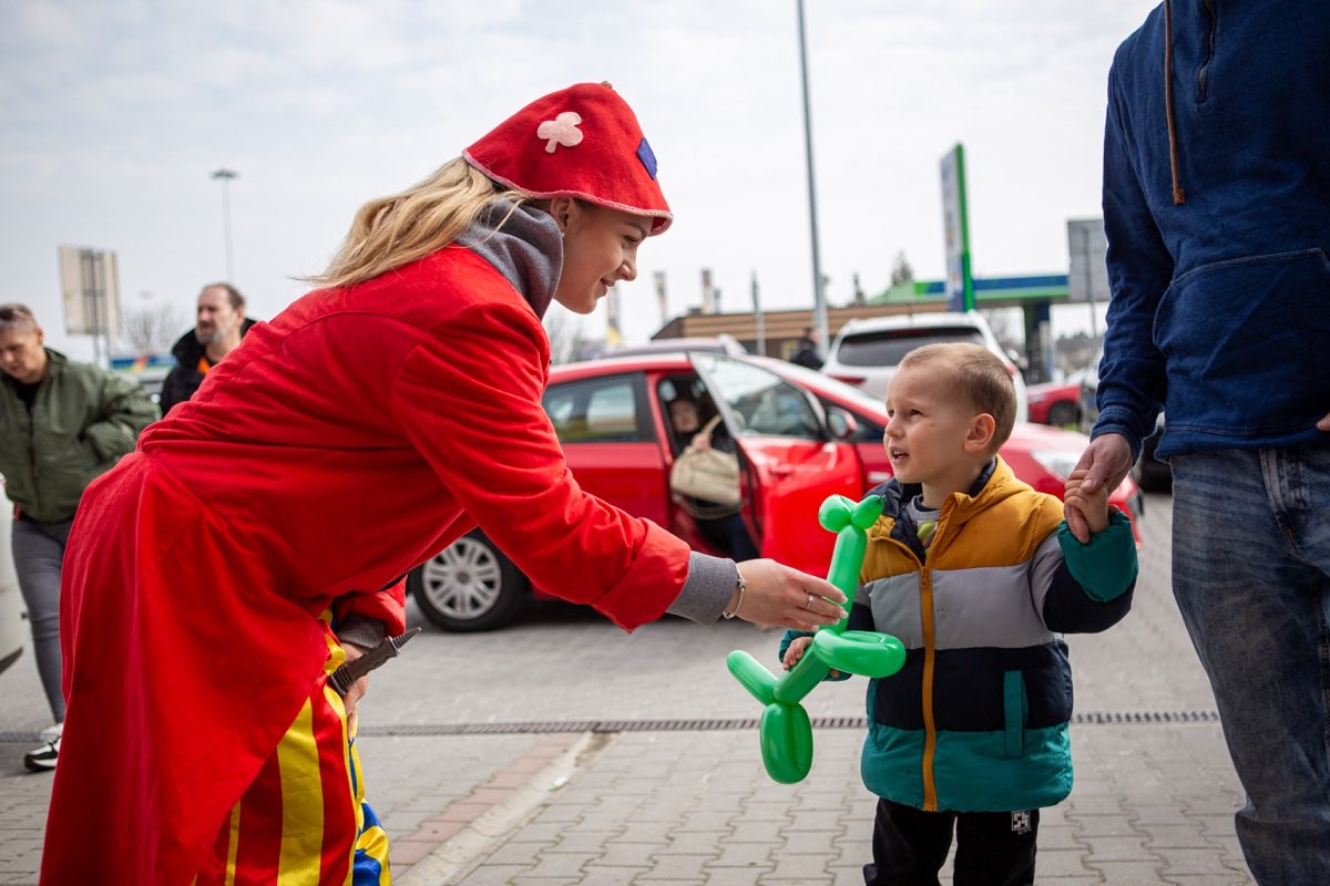 Šašo odovzdáva dieťaťu balónové zvieratko